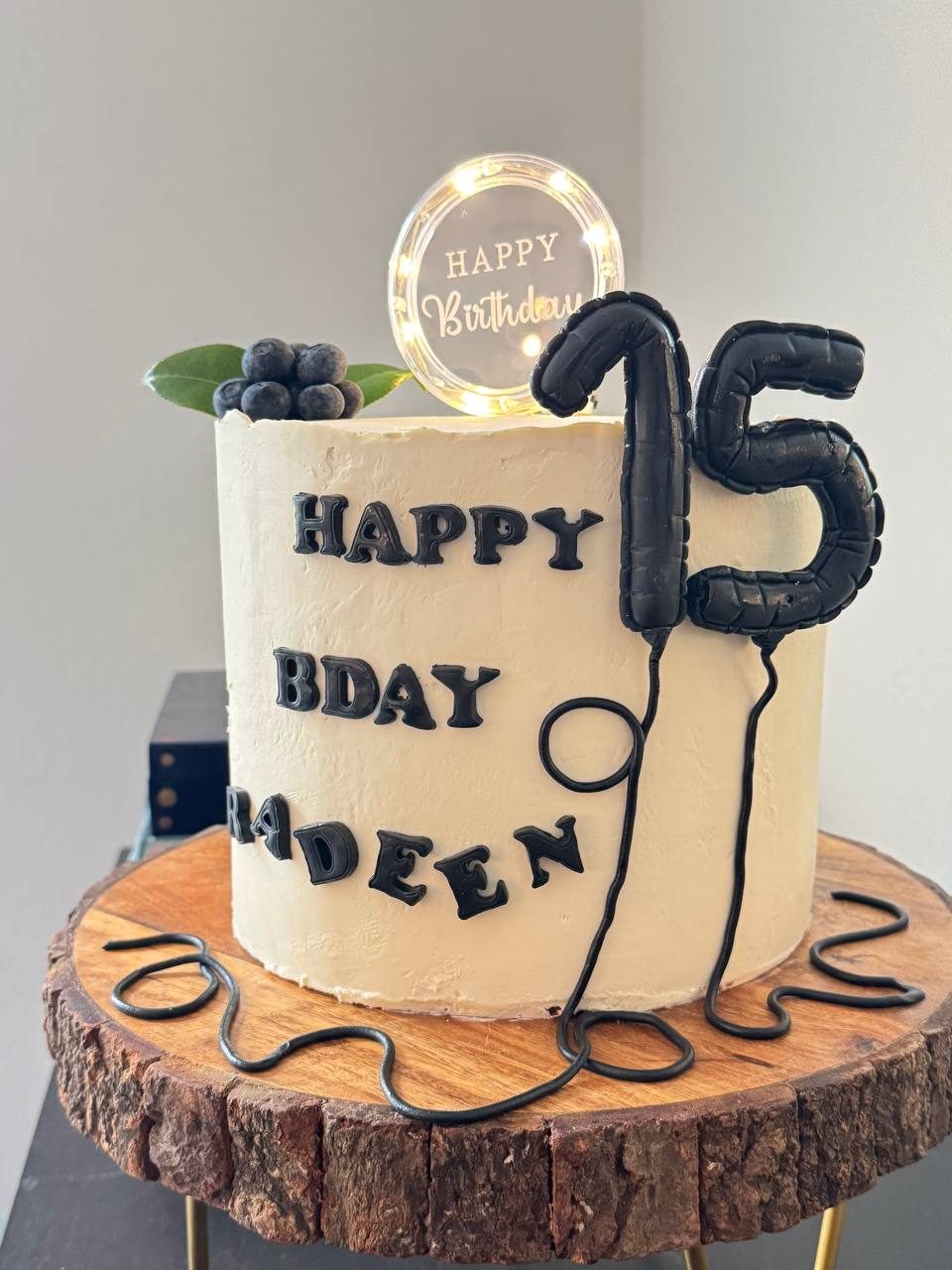 Birthday cake with a black number 15 balloon and a light-up topper