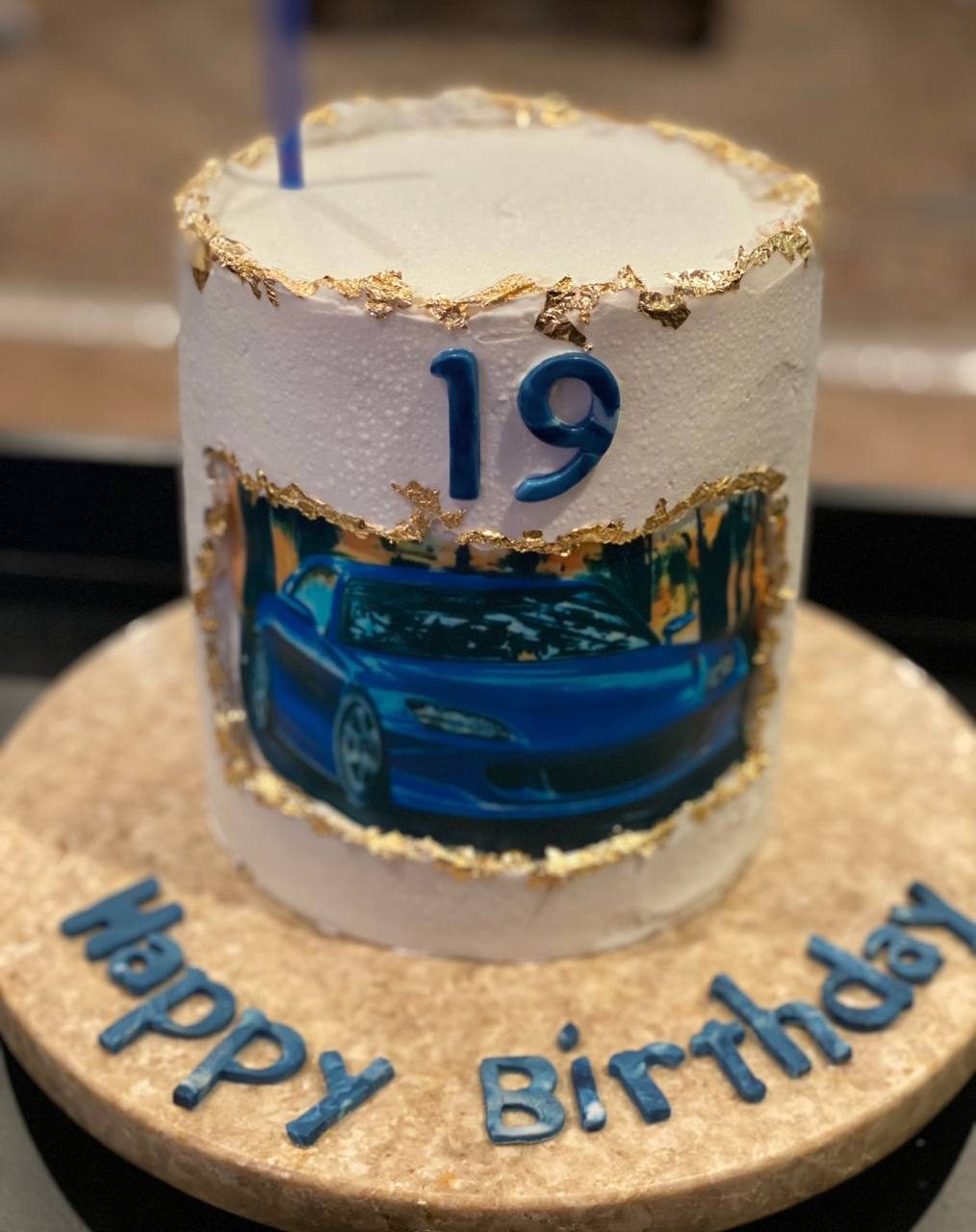 Fault-line cake with gold edges and a blue sports car, topped Happy Birthday