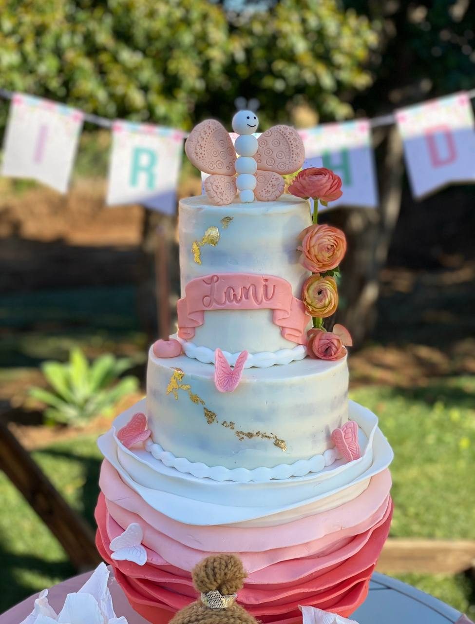 Butterfly-topped pastel birthday cake with a ruffled pink base