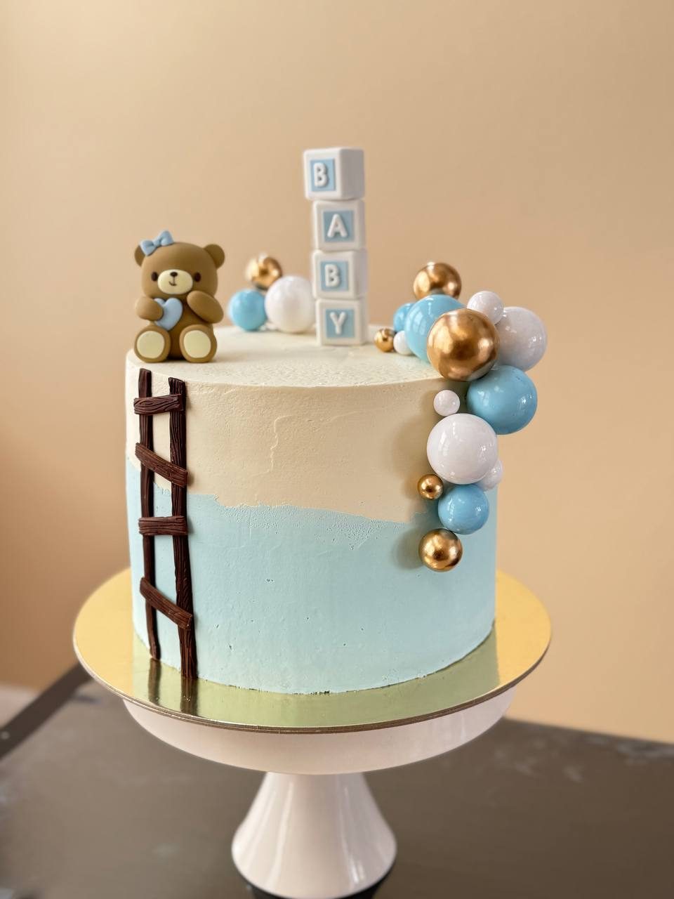 Baby shower cake with a teddy bear, baby blocks and gold spheres