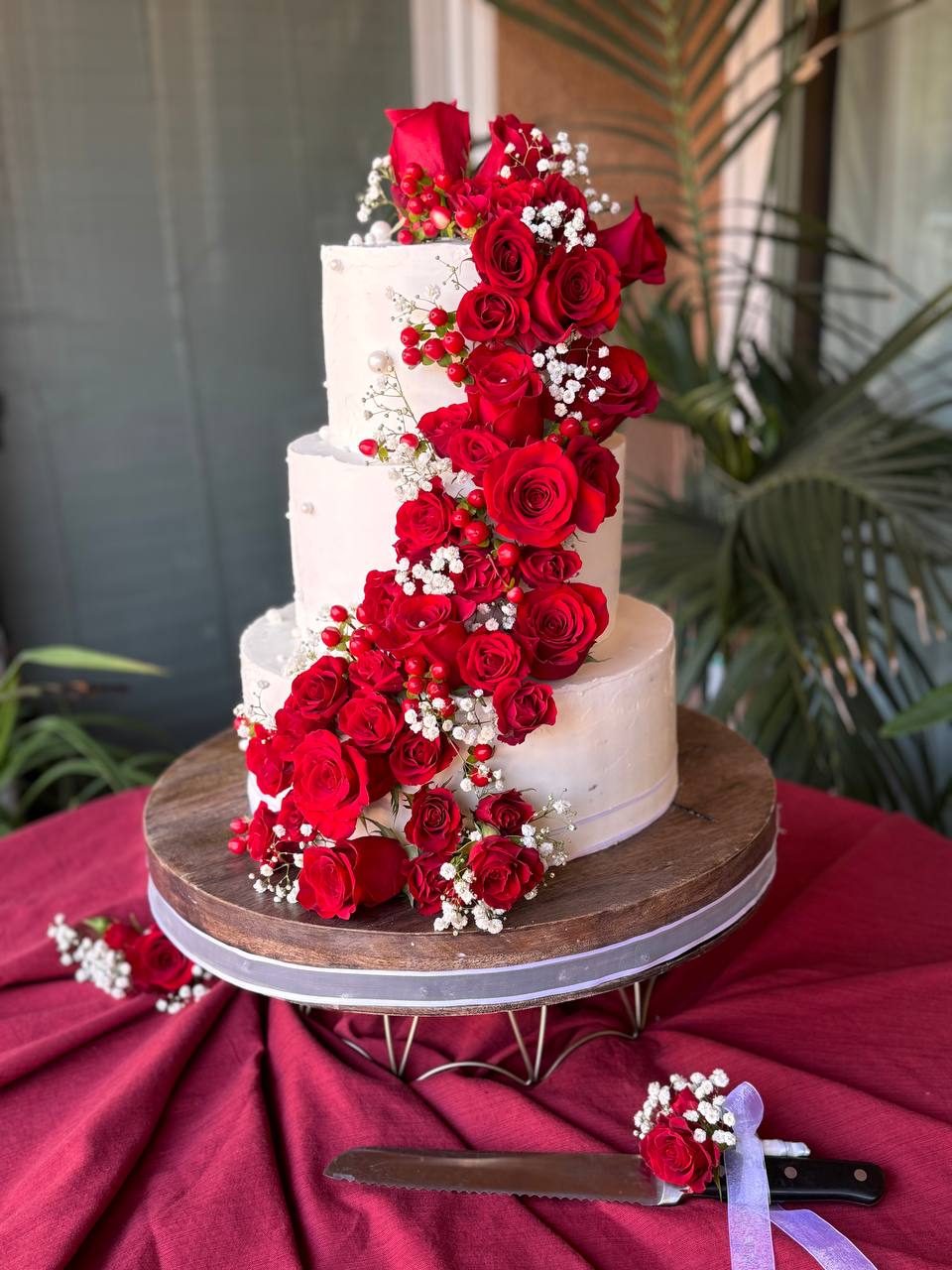 Wedding cake with a cascade of red roses and baby's breath