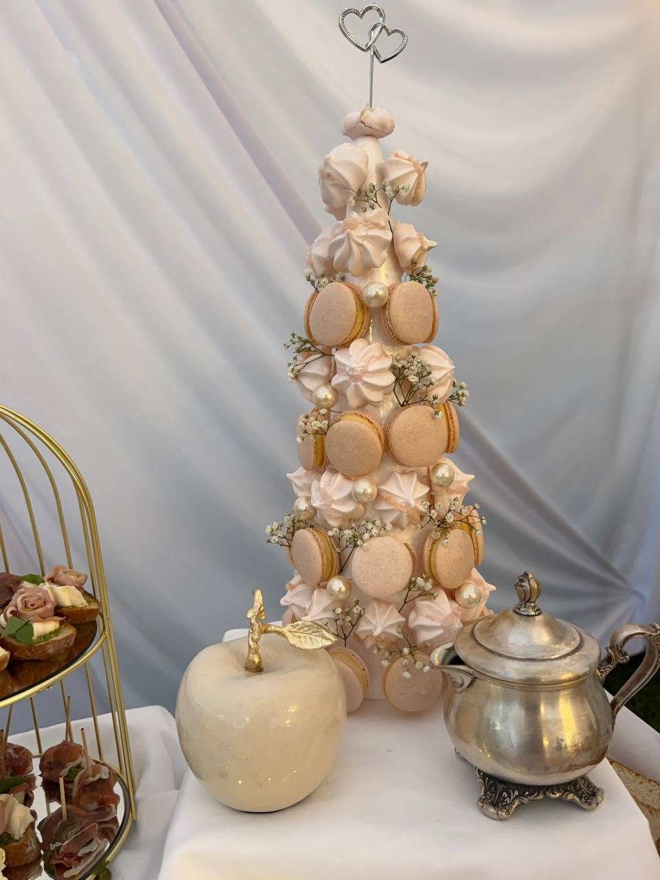Macaron and meringue tower with a heart topper beside a silver teapot