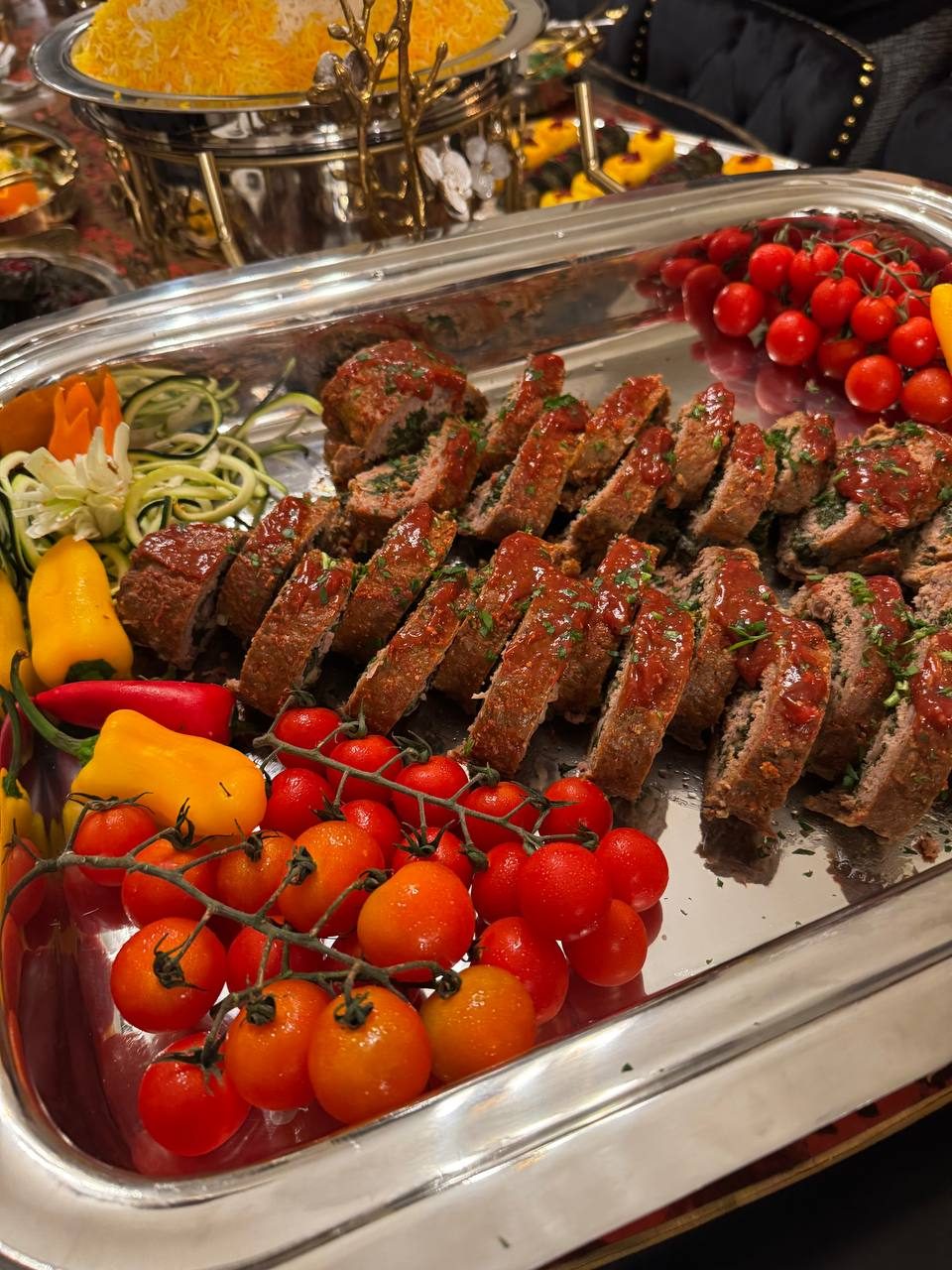 Sliced stuffed roast on a silver tray with cherry tomatoes and peppers