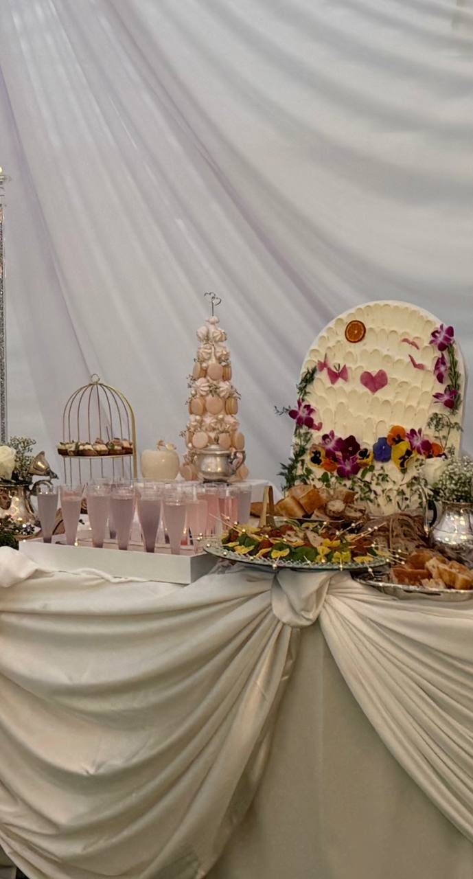 Wedding dessert table with a macaron tower and floral heart centerpiece